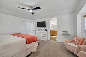 Bedroom featuring carpet flooring, a ceiling fan, arched walkways, and ensuite bath