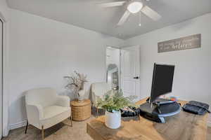 Sitting room with carpet flooring, a desk, and ceiling fan