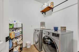 Laundry area with light tile patterned flooring and separate washer and dryer