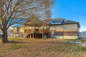 Back of property featuring brick siding, a deck, stairs, solar panels, and a gate