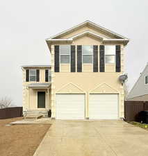 View of front facade featuring stucco siding, driveway, and an attached garage