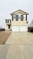 View of front facade featuring stucco siding, an attached garage, and concrete driveway