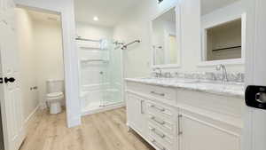 Bathroom with light wood-style flooring, double vanity, and a stall shower