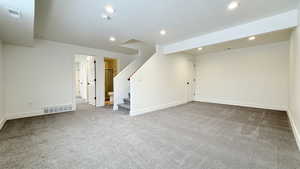 Unfurnished living room featuring stairway, light colored carpet, and recessed lighting