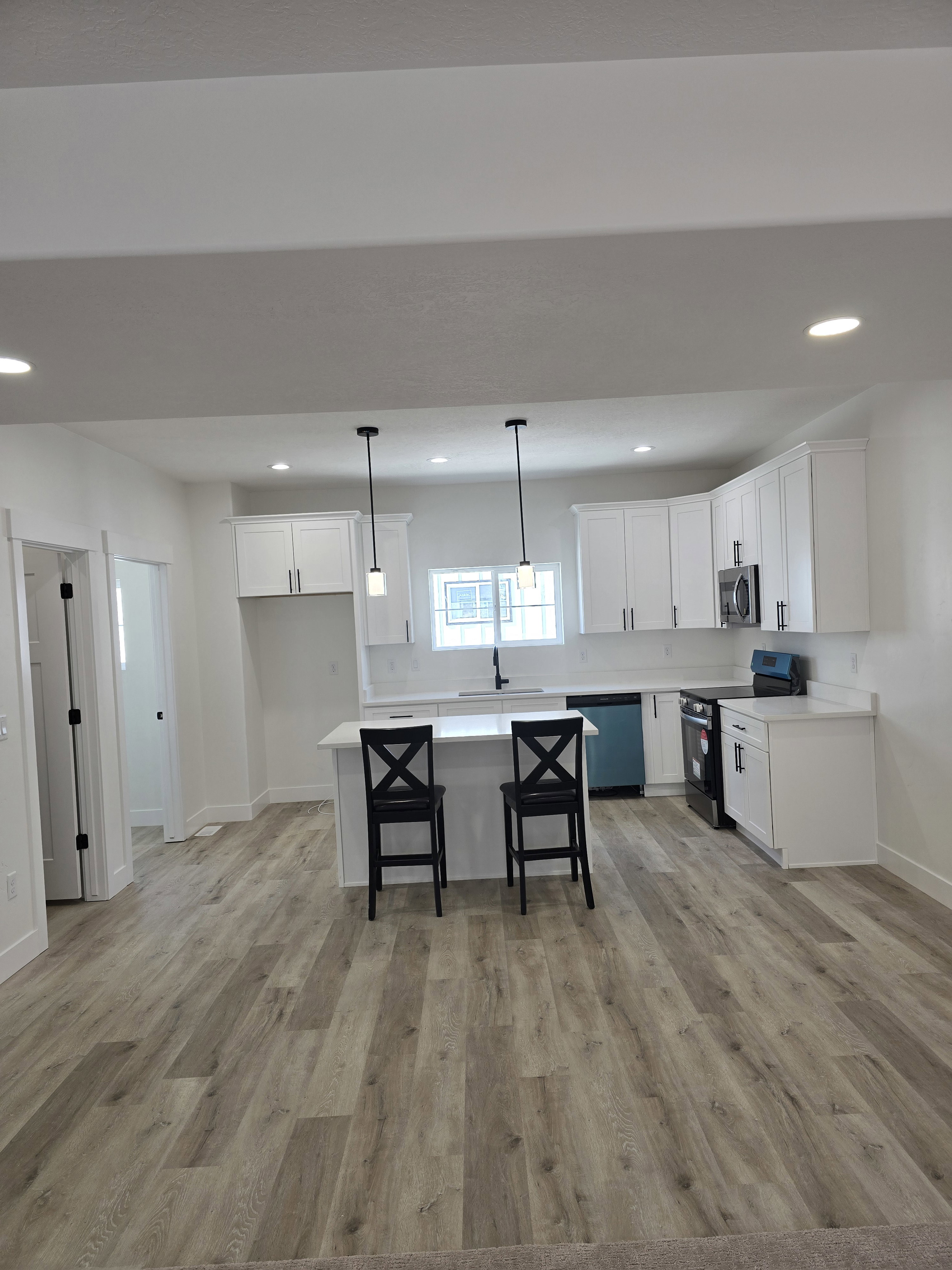Kitchen with range with electric cooktop, white cabinets, light wood-style floors, and dishwashing machine