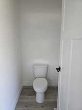 BathroomPrivate water closet featuring toilet and light wood-style floors