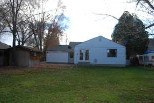 Back of house featuring a yard, a patio area, a garage, and french doors