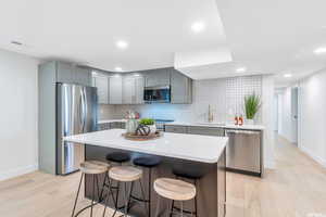 Kitchen featuring stainless steel appliances, a breakfast bar area, a kitchen island, tasteful backsplash, and recessed lighting