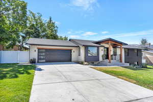 View of front of home with a shingled roof, driveway, a garage, and a gate