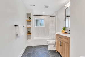 Bathroom featuring vanity, dark tile patterned floors, and shower / bath combination with curtain