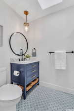 Half bathroom with vanity, a skylight, and light floors