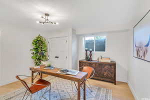 Office area featuring a chandelier, light wood-style flooring, and a textured ceiling