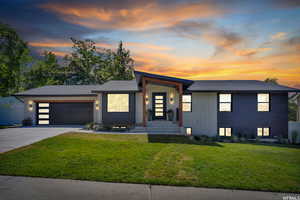 View of front of house featuring a yard, concrete driveway, a garage, and roof with shingles