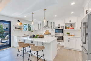 Kitchen featuring open shelves, white cabinetry, appliances with stainless steel finishes, wall chimney exhaust hood, and recessed lighting