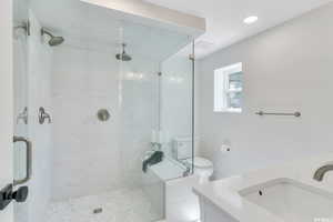 Full bathroom with vanity, a marble finish shower, and recessed lighting