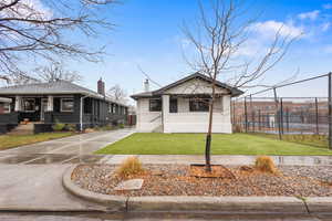 View of front of house featuring brick siding, concrete driveway, and a chimney