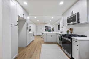 Kitchen with a peninsula, stainless steel appliances, light wood-style flooring, recessed lighting, and light stone countertops