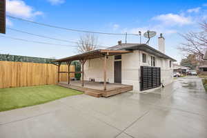 View of side of home with brick siding, a chimney, and a deck