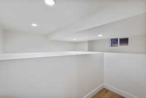 Hall with light wood finished floors and recessed lighting