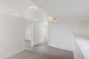 Spare room with a textured ceiling and light colored carpet