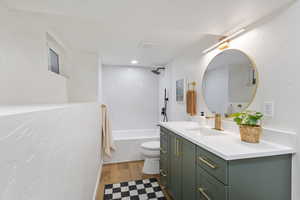 Bathroom featuring vanity, shower / bathtub combination, a textured wall, and light wood-style floors