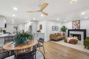 Dining room with light wood-style flooring, ceiling fan, recessed lighting, and a fireplace