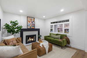 Living area with a brick fireplace, wood finished floors, and recessed lighting