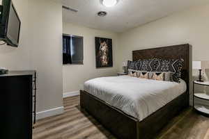 Bedroom with dark wood-style flooring and a textured ceiling