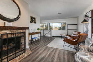 Living room with a brick fireplace and dark wood-style flooring