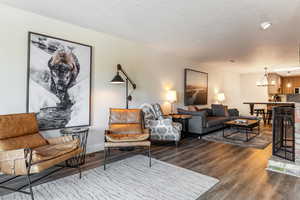 Living room with dark wood-type flooring, a textured ceiling, and a chandelier