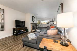 Living room with a fireplace, dark wood-type flooring, and a textured ceiling
