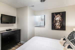 Bedroom with a textured ceiling and dark wood-type flooring