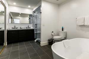 Full bathroom with a soaking tub, double vanity, a shower stall, dark tile patterned floors, and recessed lighting