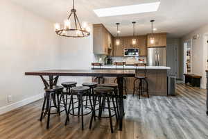Dining space featuring a skylight, a chandelier, light wood finished floors, and recessed lighting