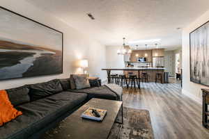 Living area with a textured ceiling, a chandelier, and light wood-style floors