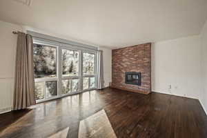 Unfurnished living room with a fireplace and dark wood-style flooring