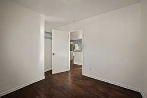 Unfurnished room featuring baseboards and dark wood-style flooring