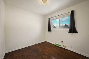 Spare room with dark wood-style flooring and baseboards