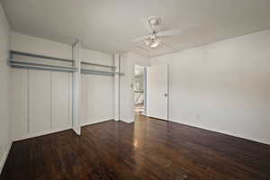 Unfurnished bedroom featuring a ceiling fan, dark wood-style floors, and a closet