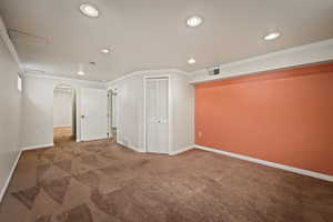 Unfurnished room with arched walkways, carpet flooring, crown molding, and recessed lighting