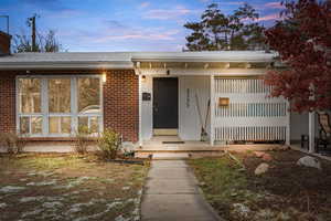 Exterior entry at dusk with brick siding, board and batten siding, and roof with shingles