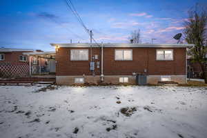 Snow covered house featuring a patio area and brick siding