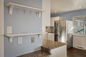 Kitchen with stainless steel fridge, backsplash, white cabinets, dark wood finished floors, and recessed lighting