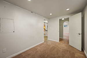 Carpeted empty room featuring arched walkways and recessed lighting