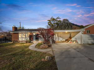 View of front of home featuring a chimney, brick siding, and concrete driveway