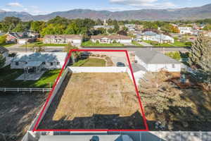 Aerial view of residential area featuring a mountainous background and property parcel outlined