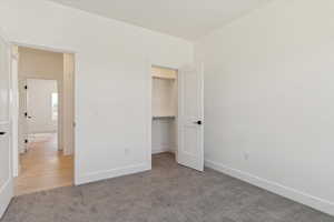 Unfurnished bedroom featuring light carpet and a spacious closet