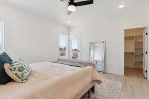 Bedroom with light wood finished floors, a walk in closet, a ceiling fan, access to outside, and recessed lighting