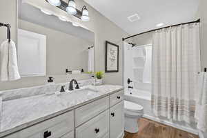 Full bath with shower / bath combo with shower curtain, vanity, and light wood finished floors