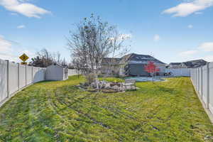 Fenced backyard with an outdoor fire pit and a shed.